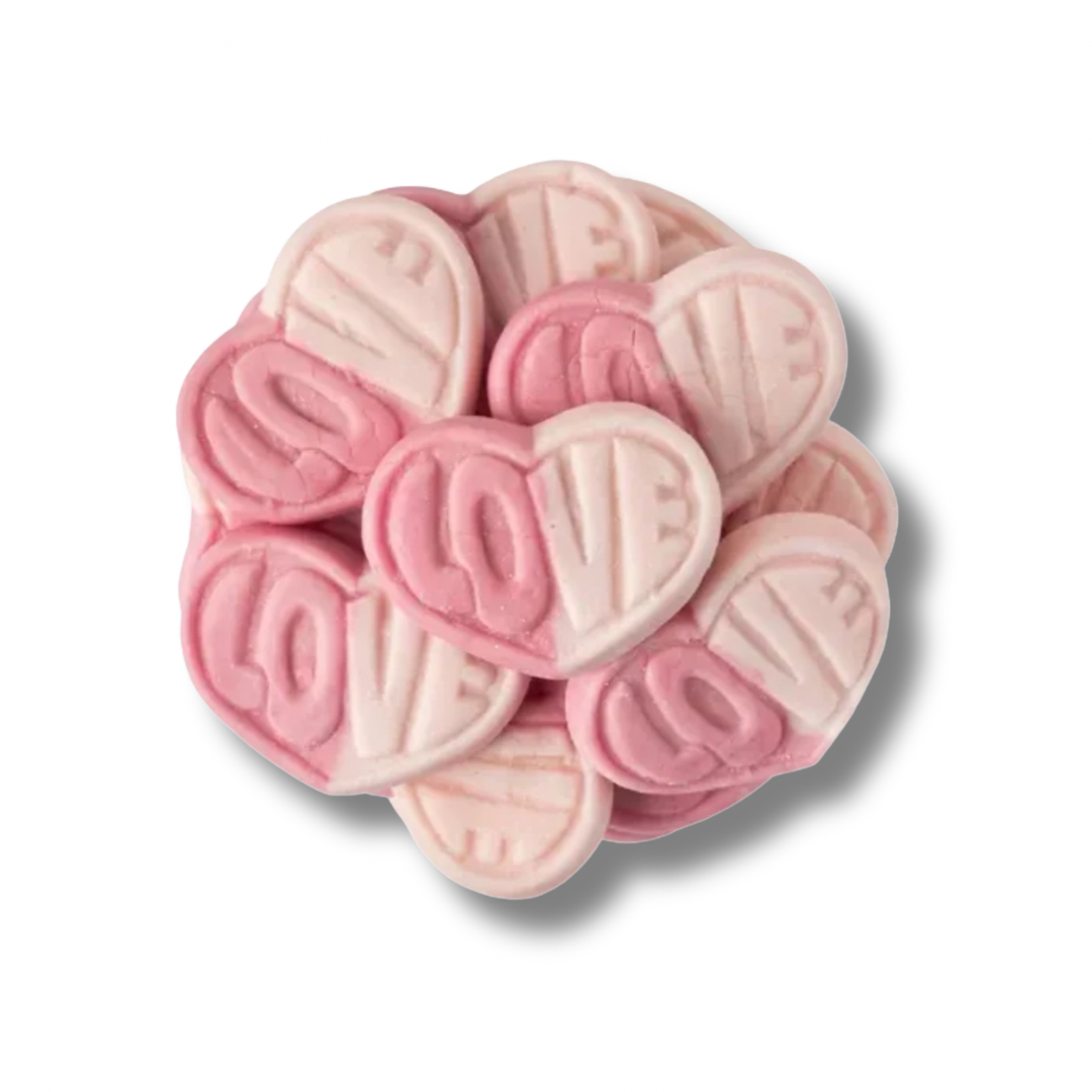 Pink heart-shaped candies with 'LOVE' on a white background